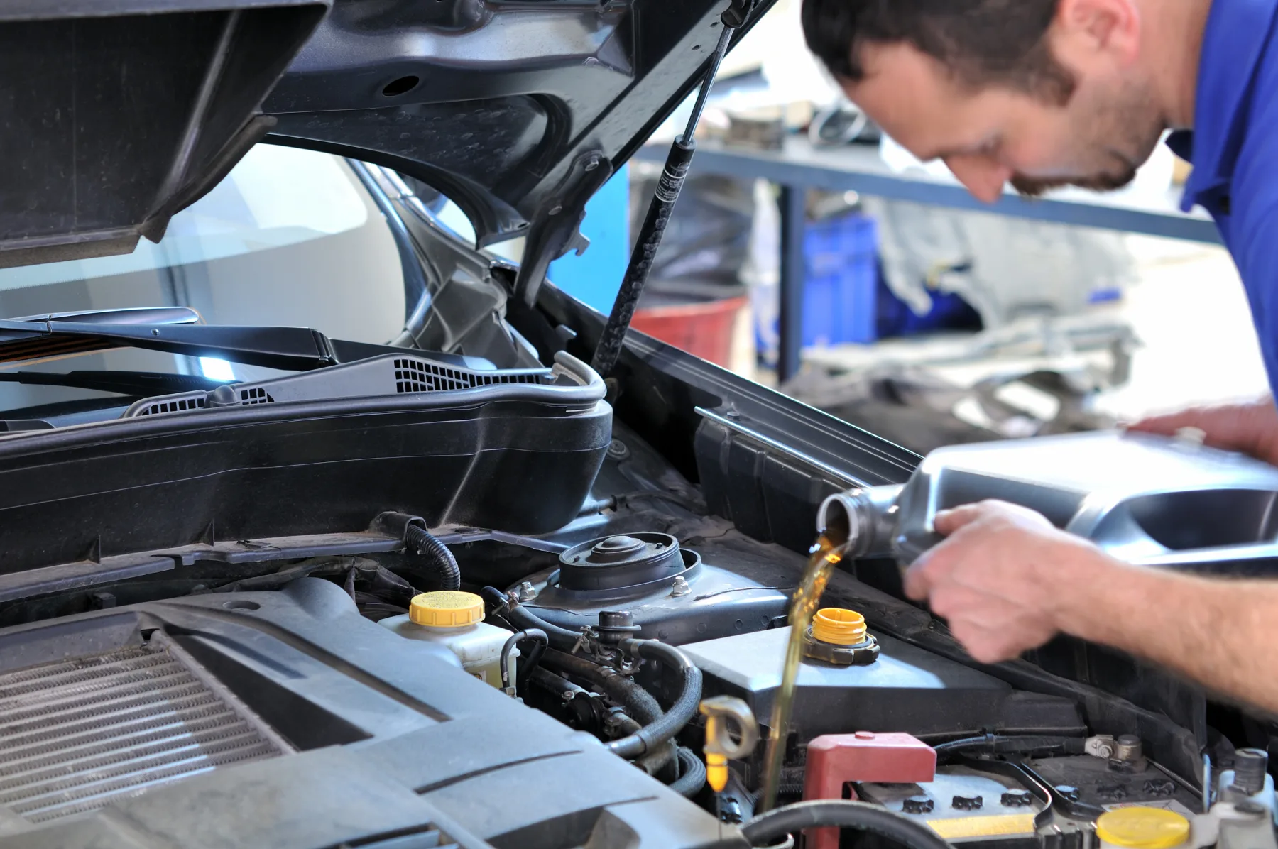 Mechanic pouring fresh engine oil into a car during a service